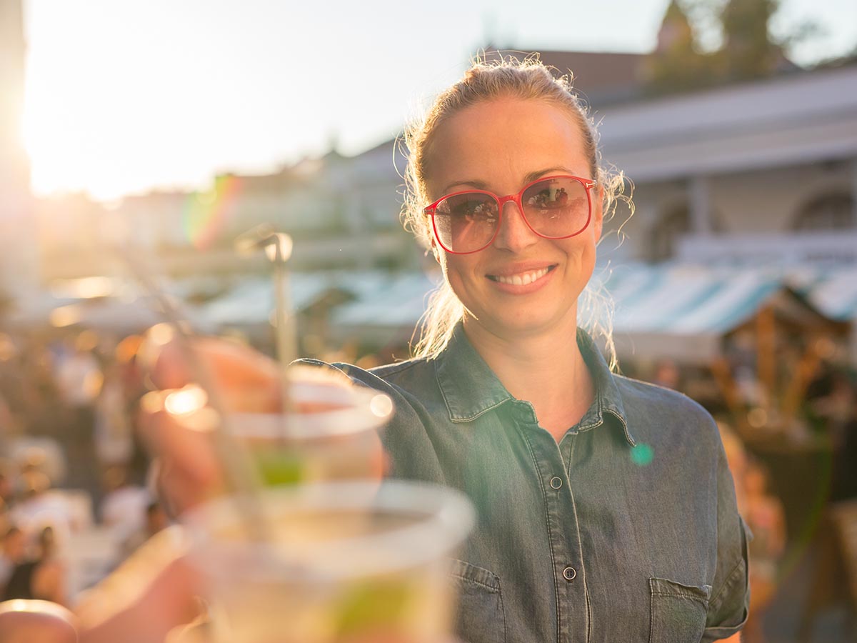Smiling woman toasting beverage at an outdoor event