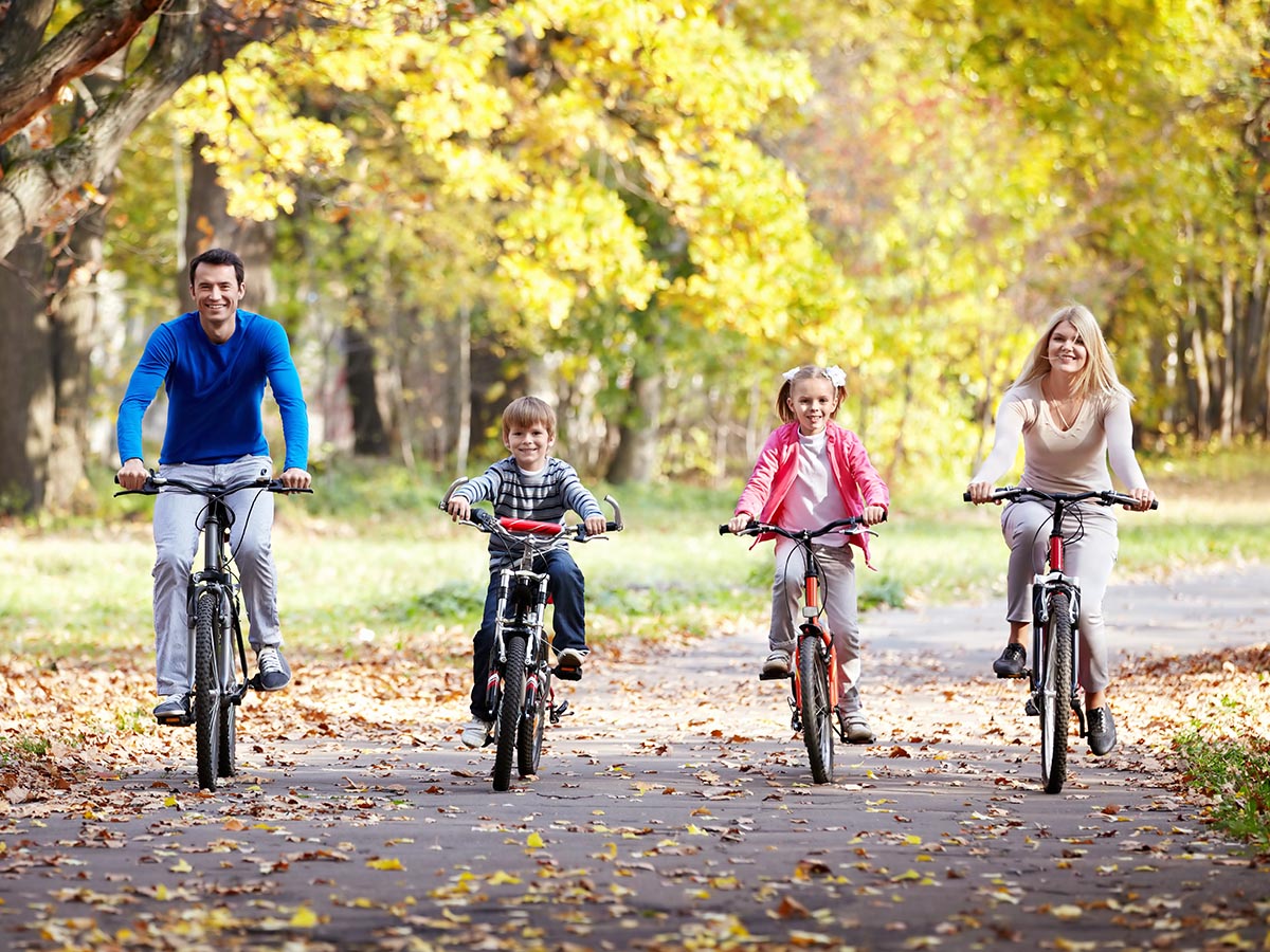 Family riding their bikes in the park in the fall